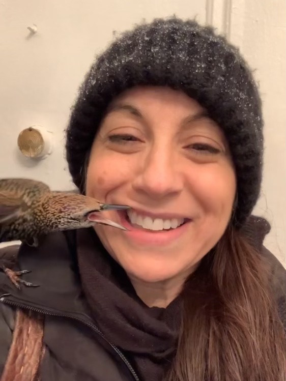 Harley Brooks smiling with a bird perched on her shoulder