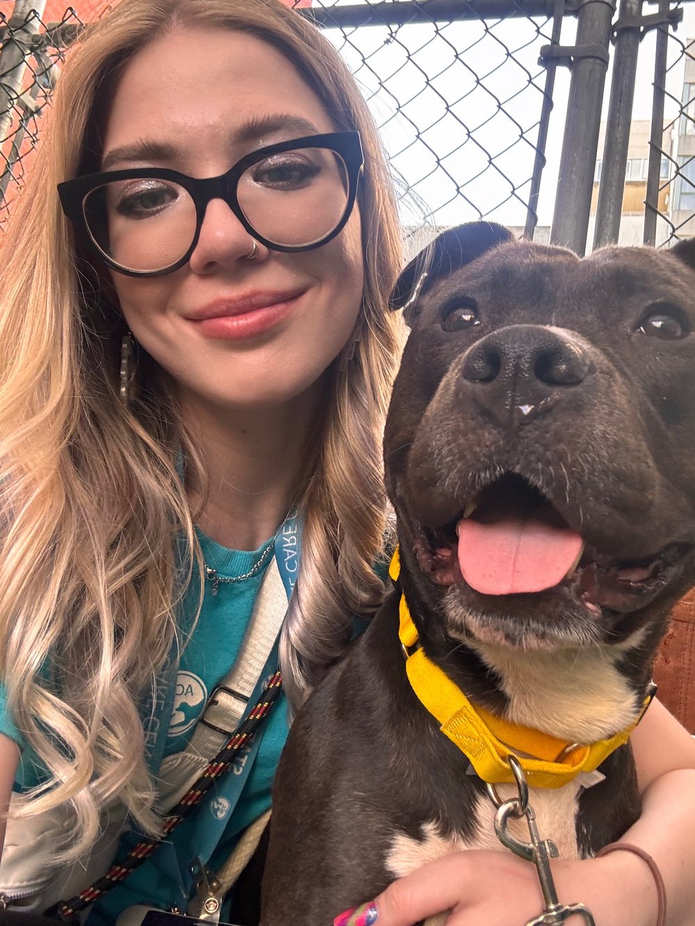 Yulia Kushnir with a smiling black dog in a yellow collar